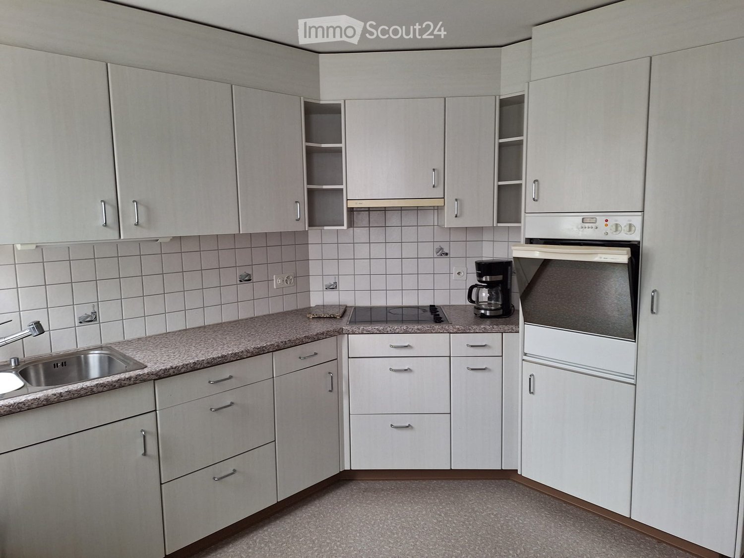 modern kitchen, white cabinets, granite countertop, silver sink, electric stove, coffee maker, double oven