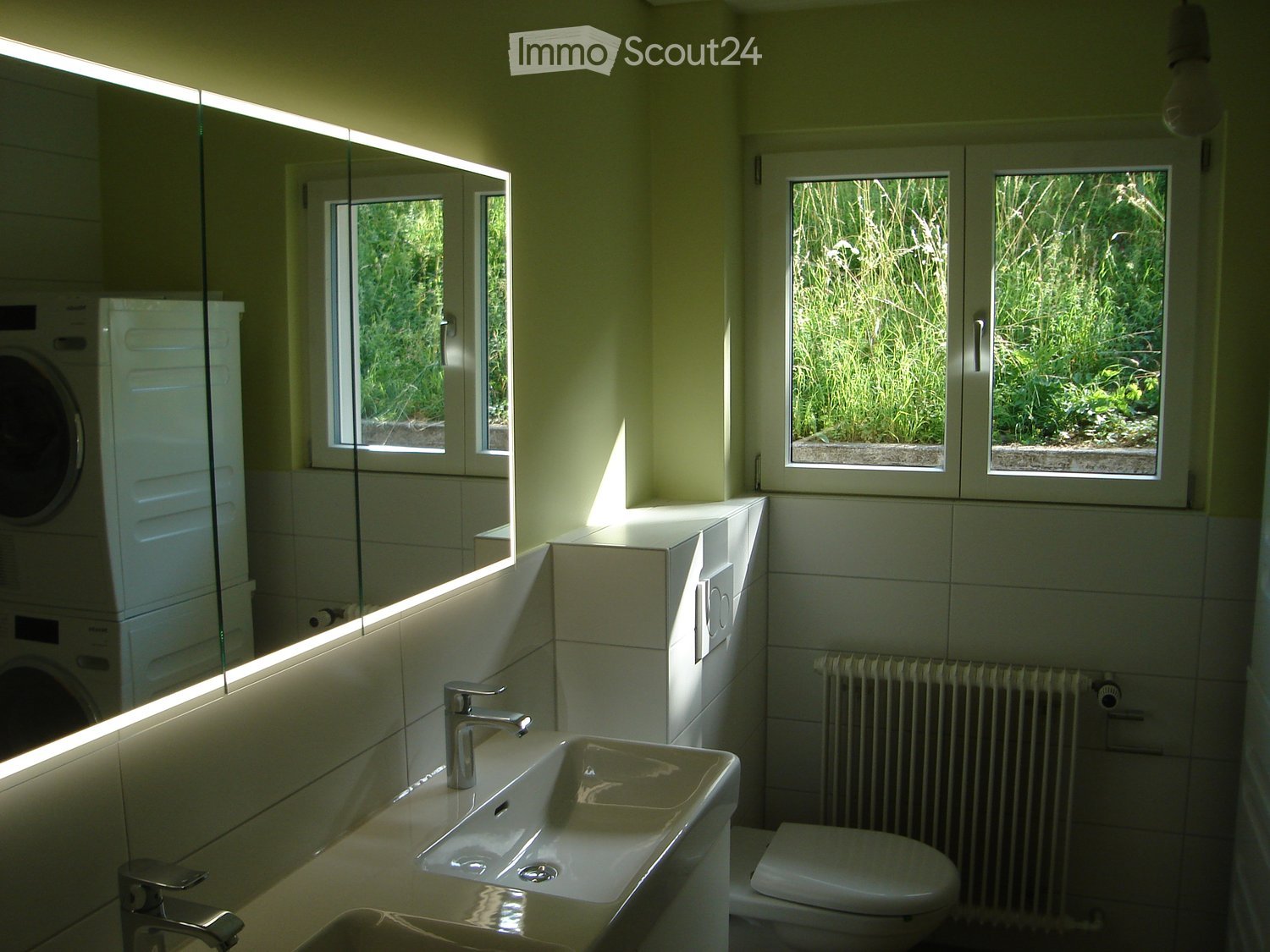 White walls, white tiled floor, vanity with a sink and mirror, toilet, heater, large windows