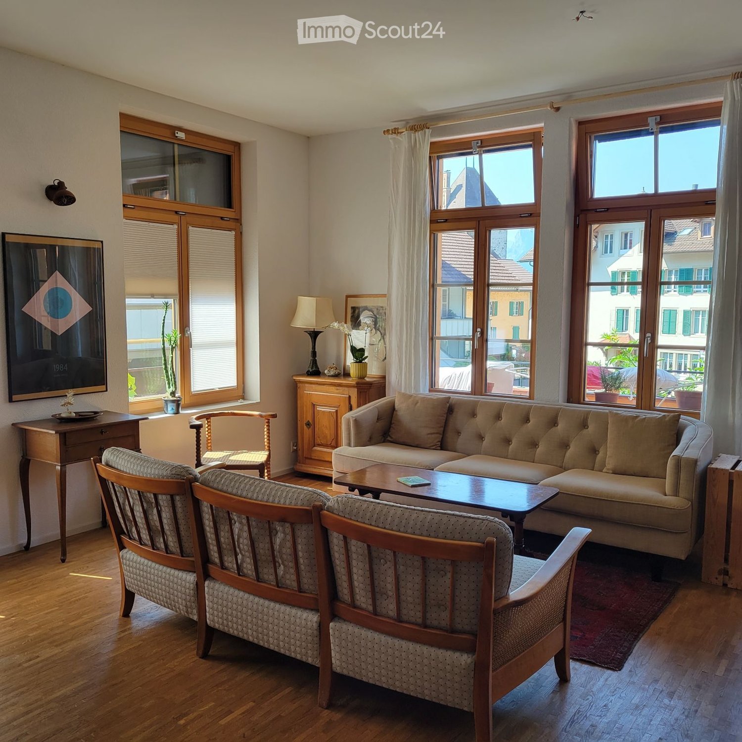 living room, beige couch, wooden side table, wooden chairs, wooden floor, windows