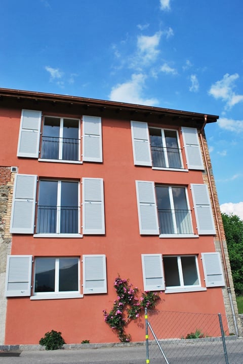 Red building, white shutters, multiple windows, balconies