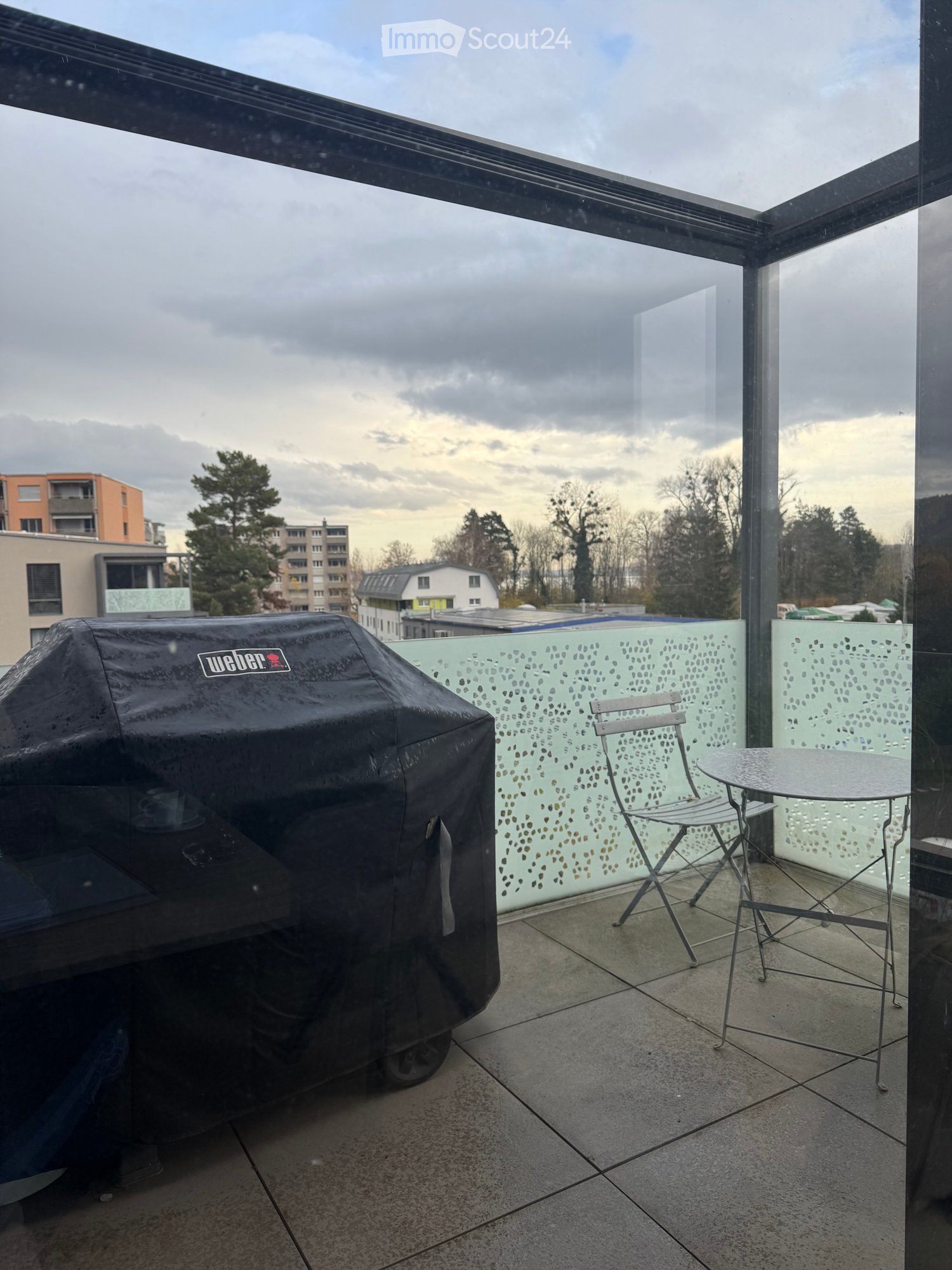 covered terrace, Weber barbecue, metal chairs, round table, lattice fence, urban view