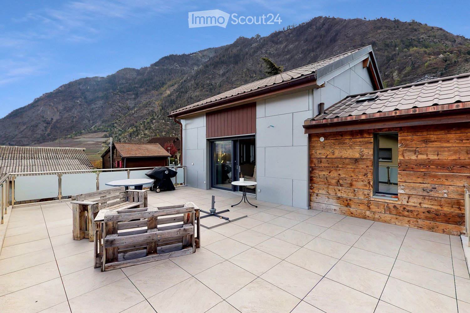 Outdoor terrace with wooden furniture, tiled floor, and mountain view