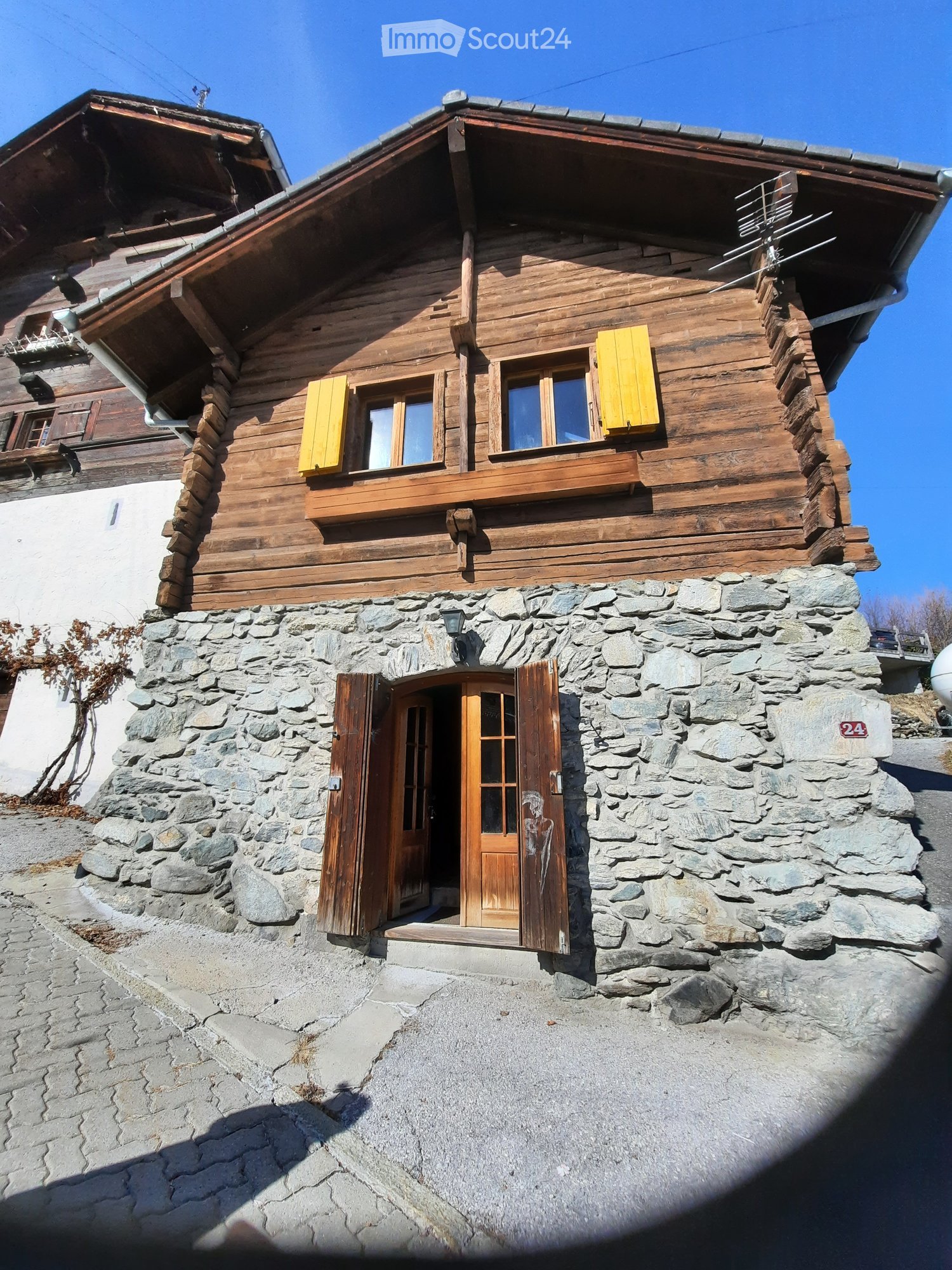 Traditional wooden house, two floors, stone ground floor, wooden walls, windows with yellow shutters, wooden door