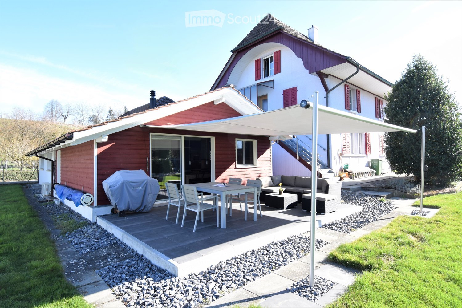 Detached house, red exterior, terrace, outdoor dining area, gravel pathway, grassy lawn