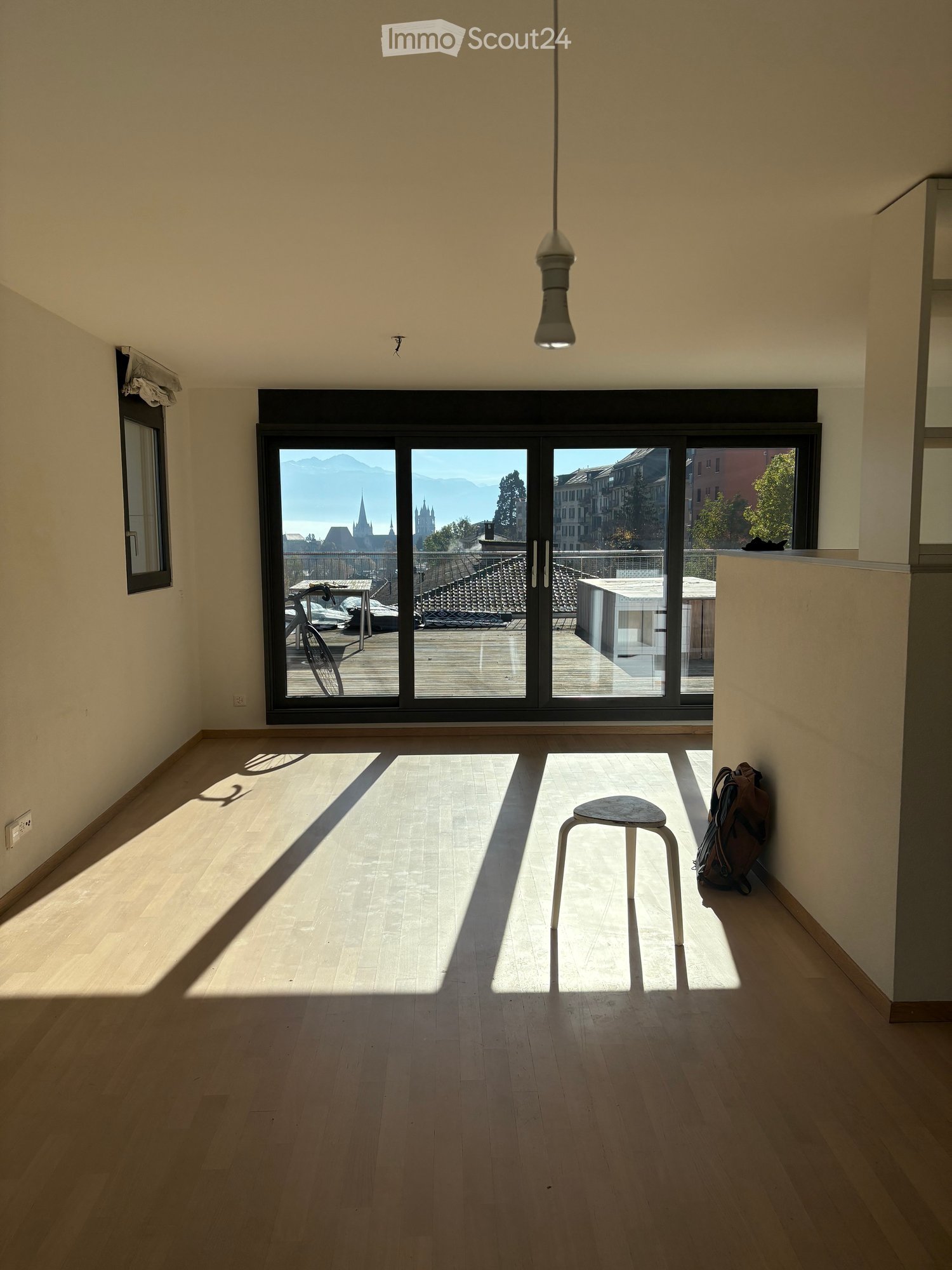 wooden floor, large windows, balcony, outside view of the city, white wall