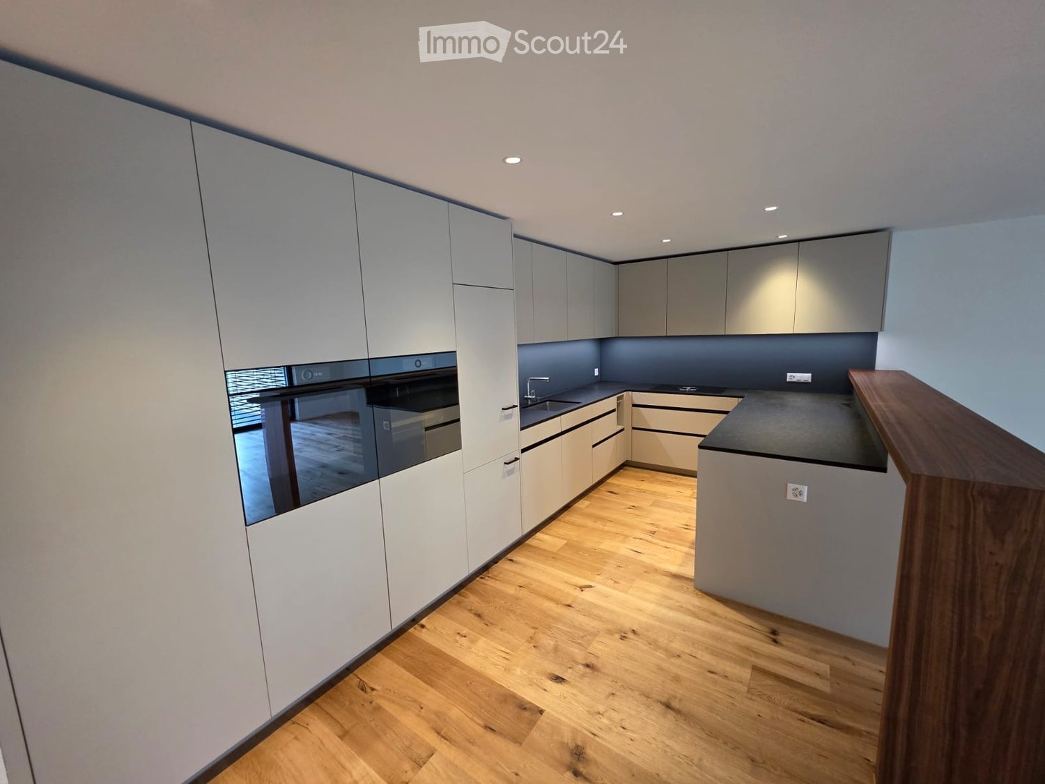 modern kitchen, white cabinets, wooden floor, black countertops, double oven