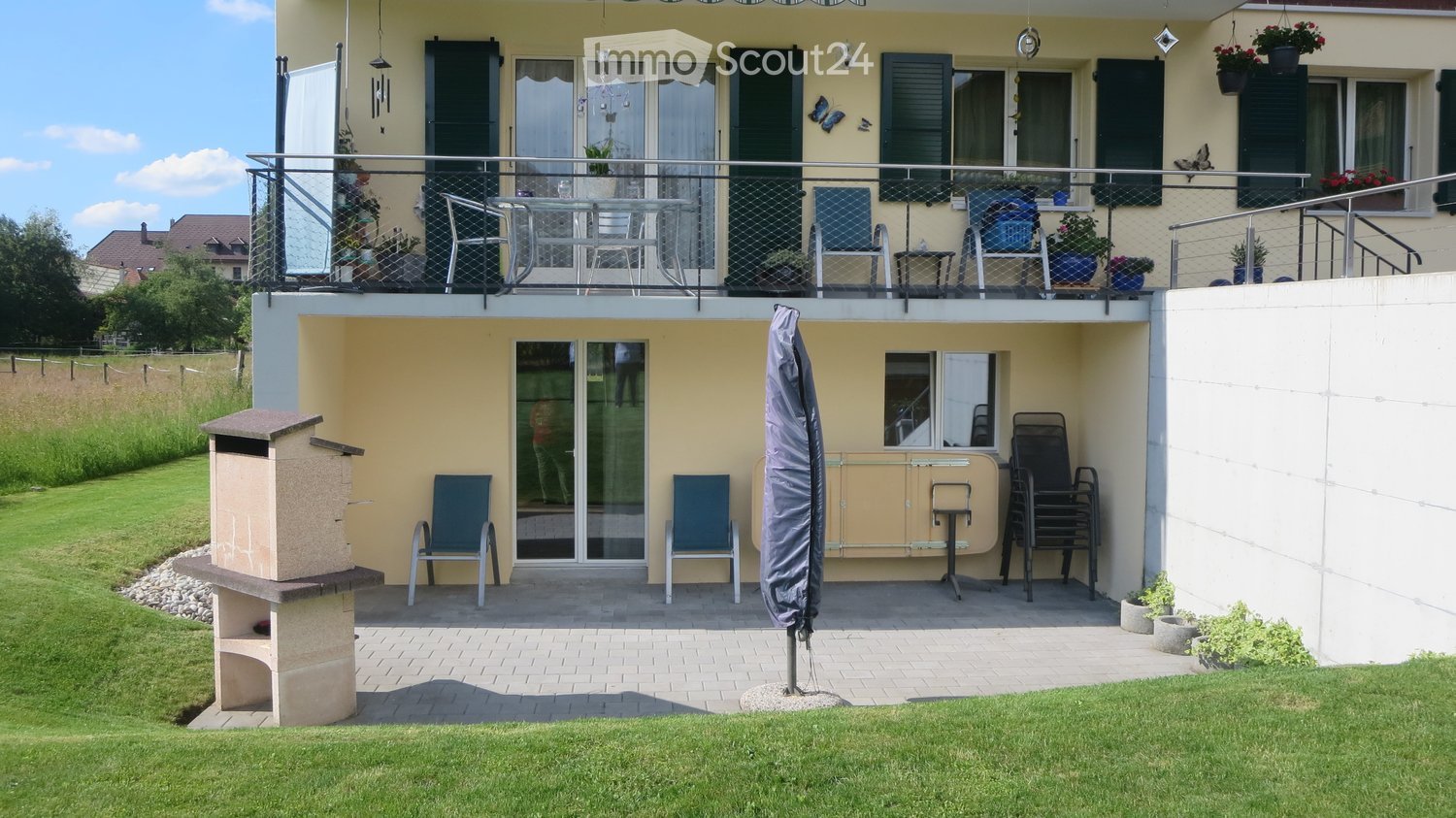 2-storey house with balcony and raised ground floor, featuring multiple outdoor seating areas, large lawn and a pergola