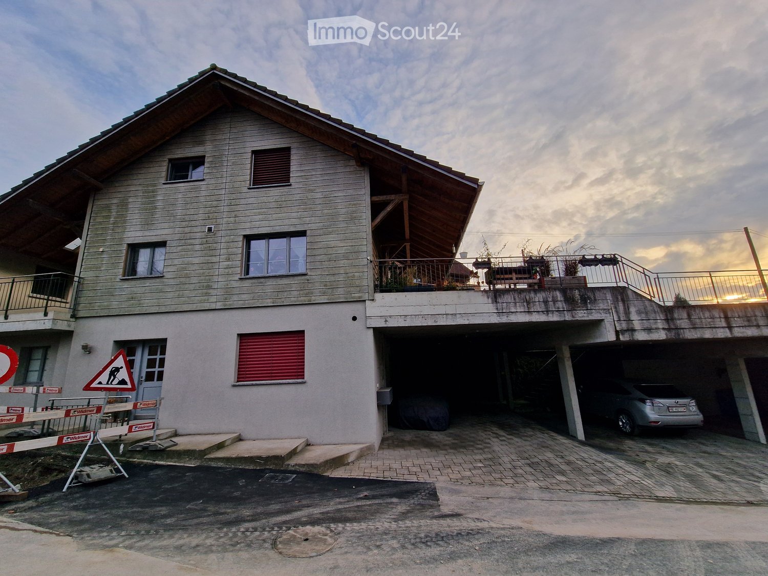 Two-story house, wooden exterior, red shutters, garage, balcony with plants