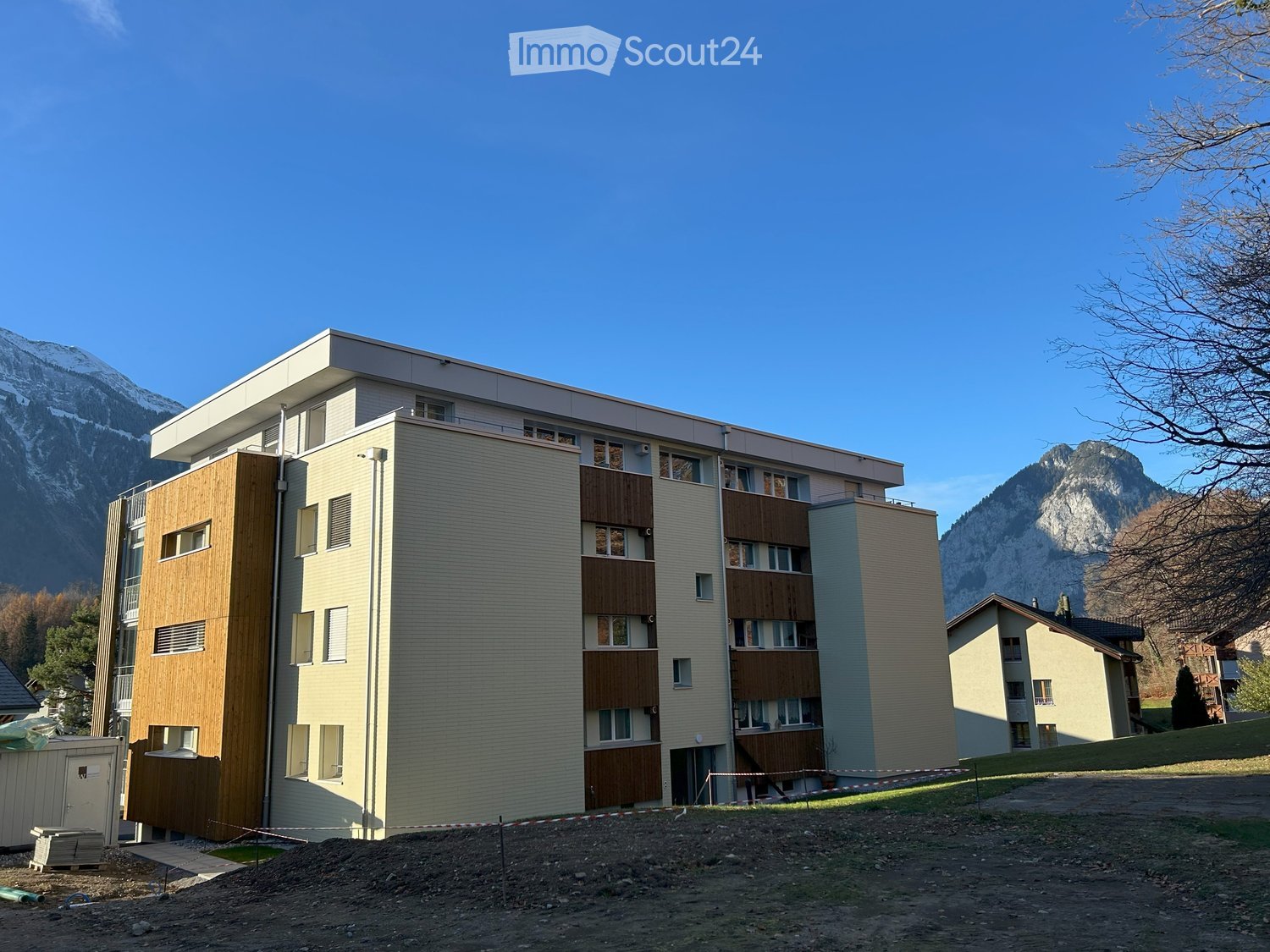 apartment building, beige and brown walls, several windows, ground floor with covered balcony