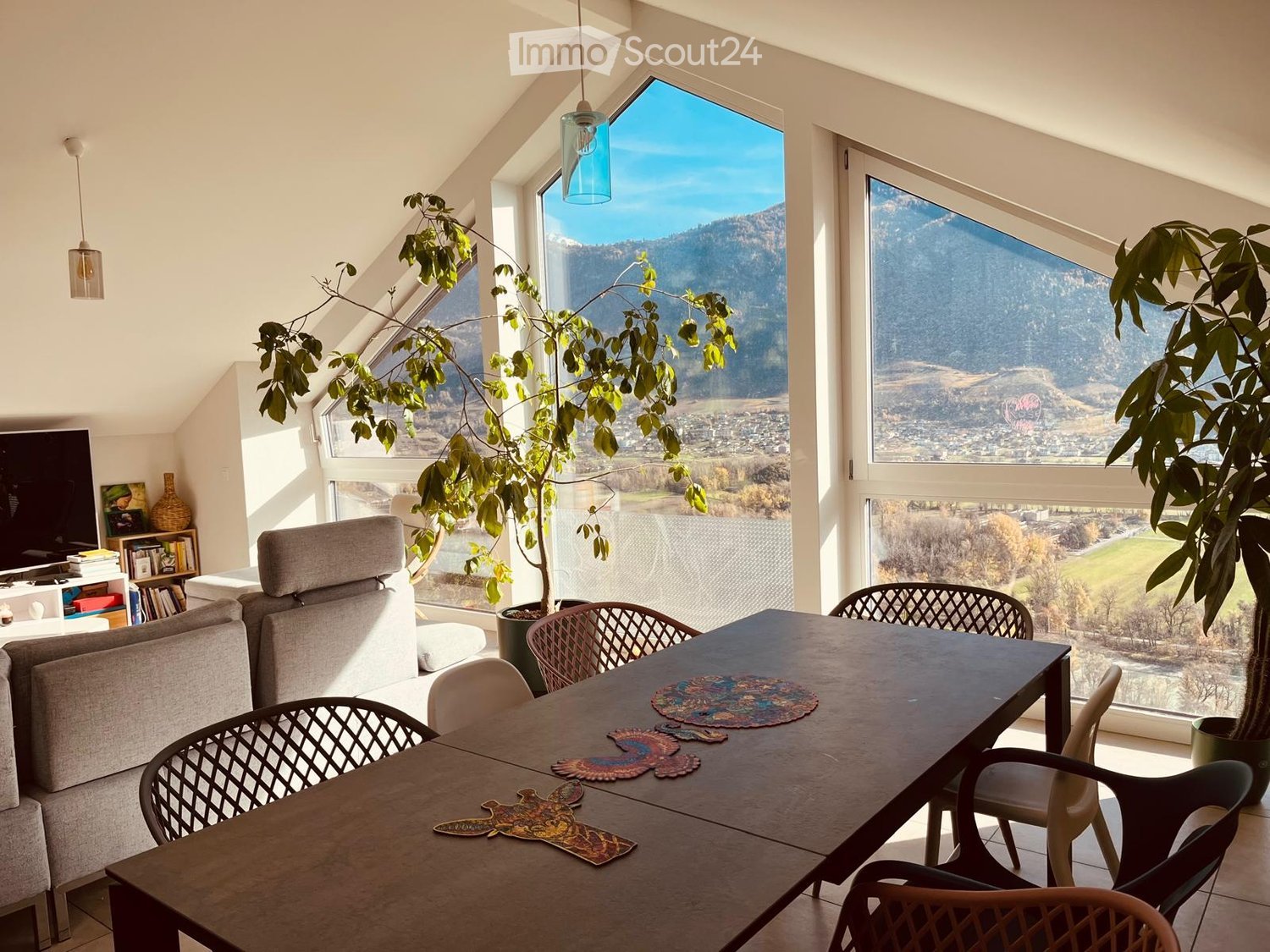 modern dining area with large windows, mountain view, dining table with coasters, plants