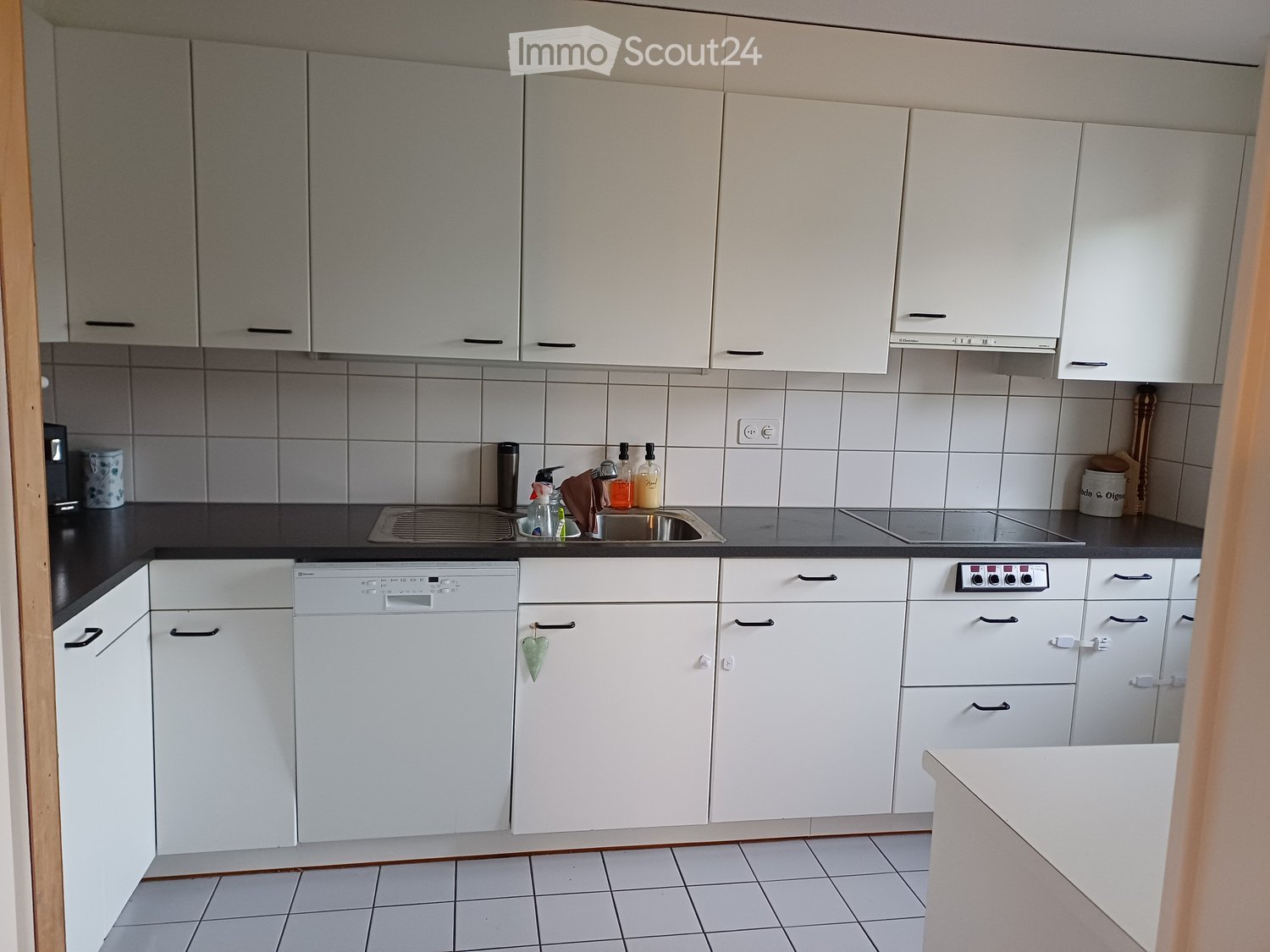 Modern kitchen with white cabinets, tile flooring, a sink, dishwasher, and built-in appliances