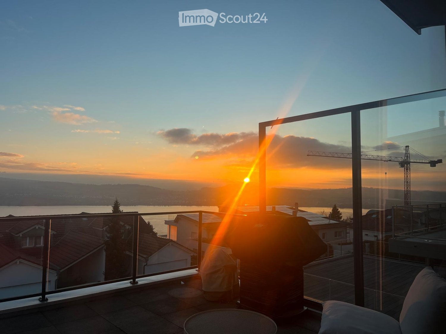 A sunset view from a terrace, balcony with metal railing, and a view of a city and river.