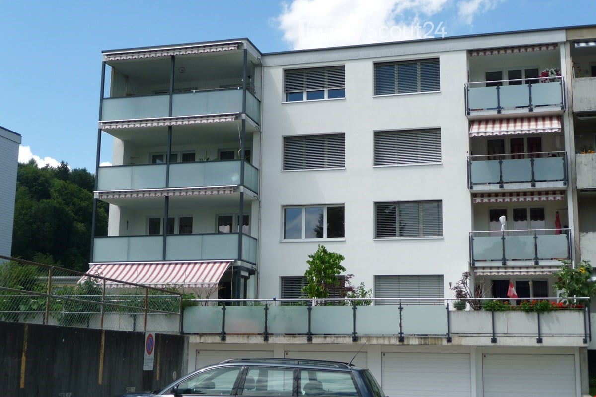 4-story apartment building, white exterior, balconies, garages at the ground level