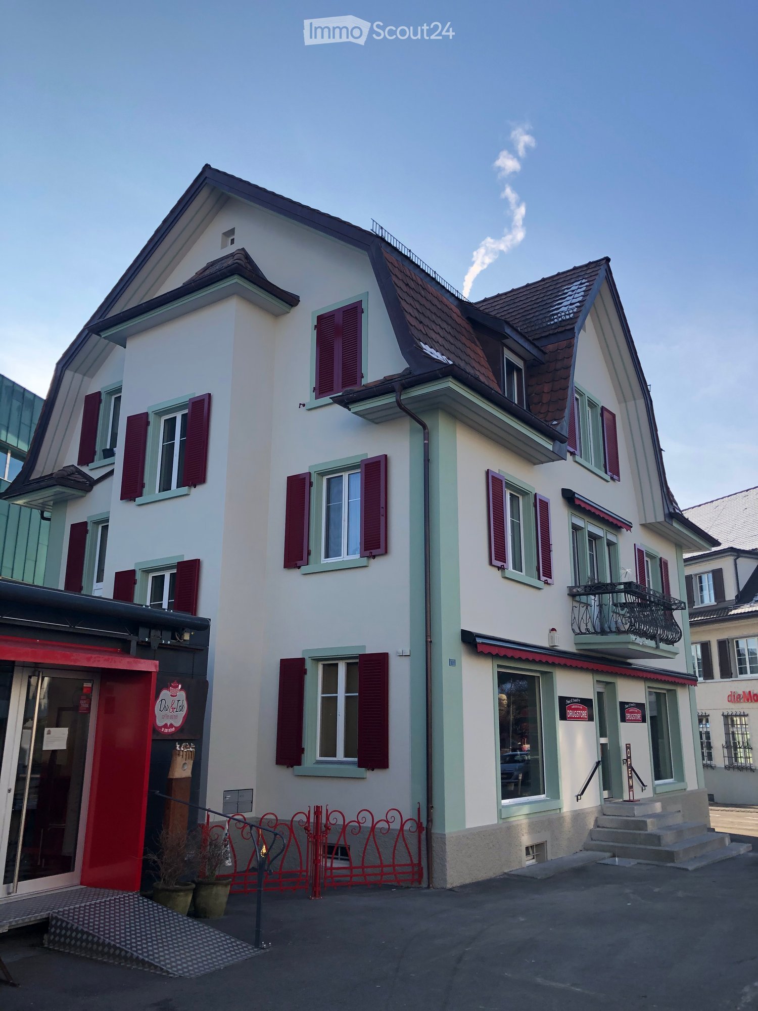 white building, brown roof, red shutters, balcony, red fence