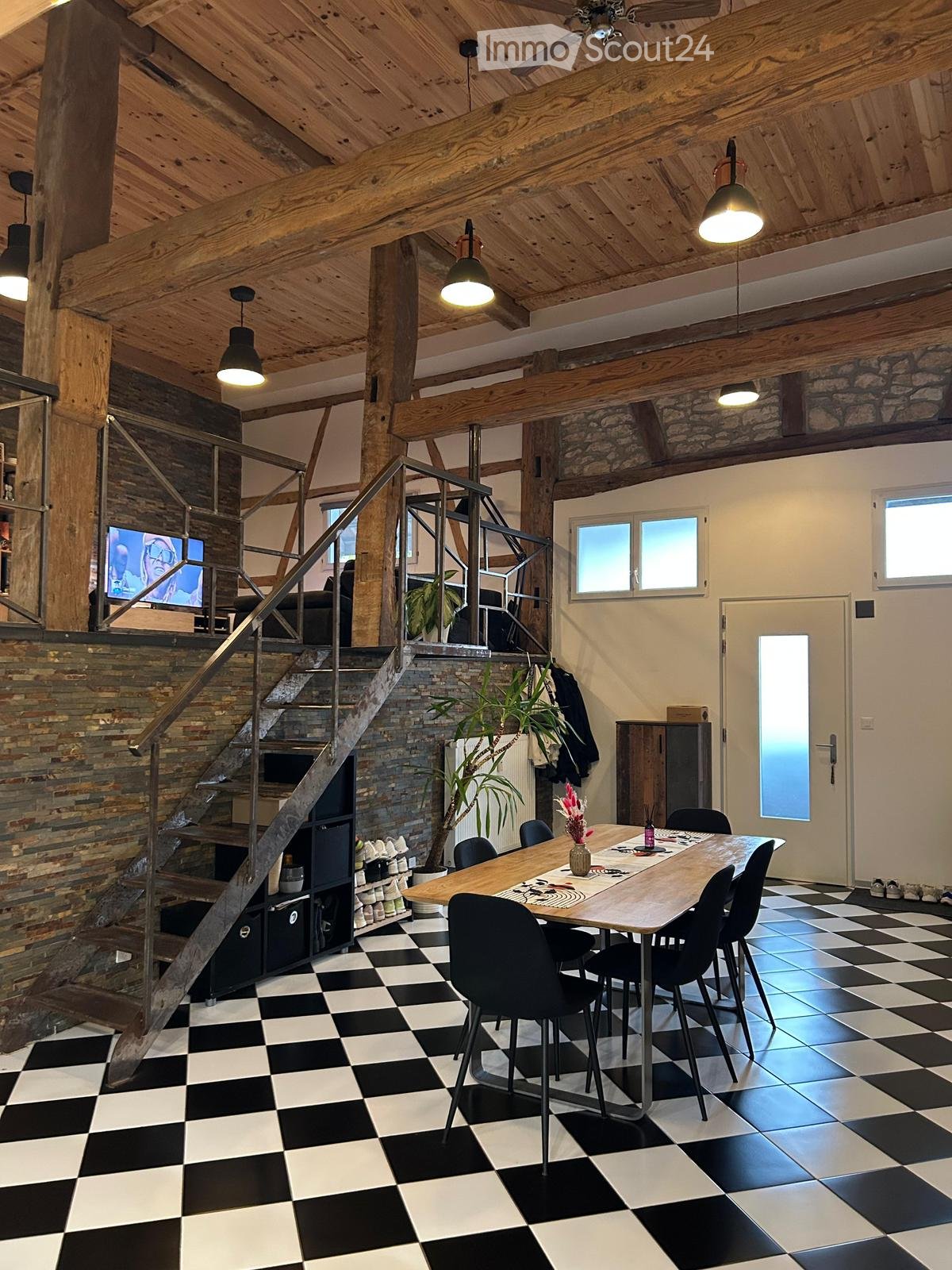 wooden beams, checkered floor, white walls, dining table with 6 chairs, staircase, metal railing