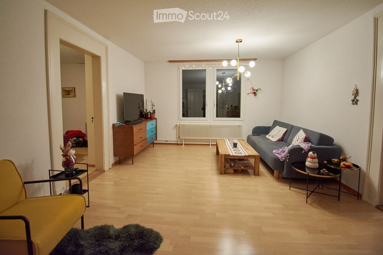 wooden floor, large gray sofa, wooden coffee table, brown cabinet, flat screen TV