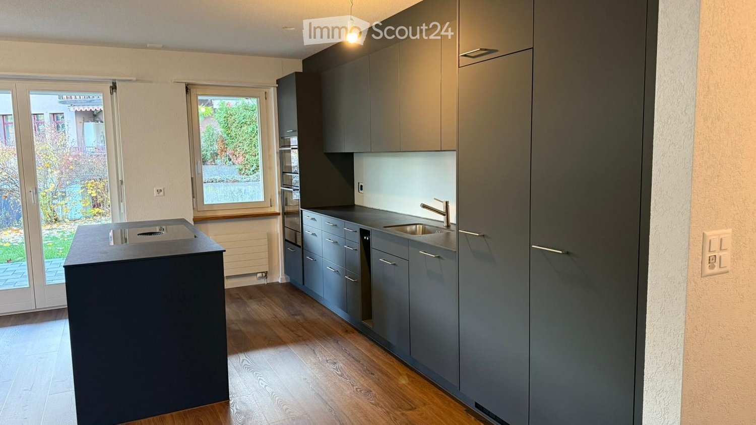 Open kitchen with modern design, island, central sink, large glass windows
