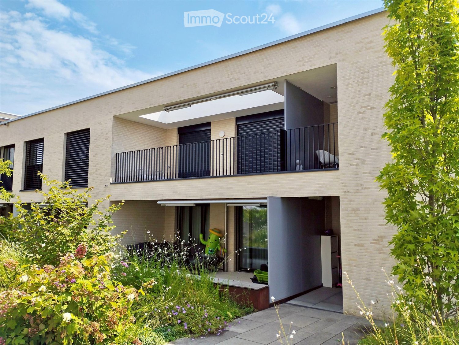 modern building with brick walls, large balcony, multiple windows, entry gate