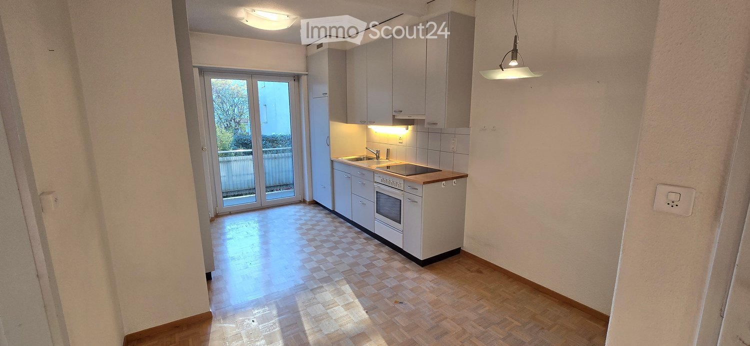 empty kitchen with white tiled walls, wooden floor, double doors to the balcony, and modern appliances