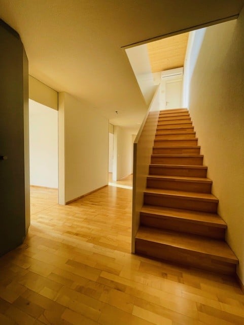 Wooden floor, wooden stairs, white walls, open to another room