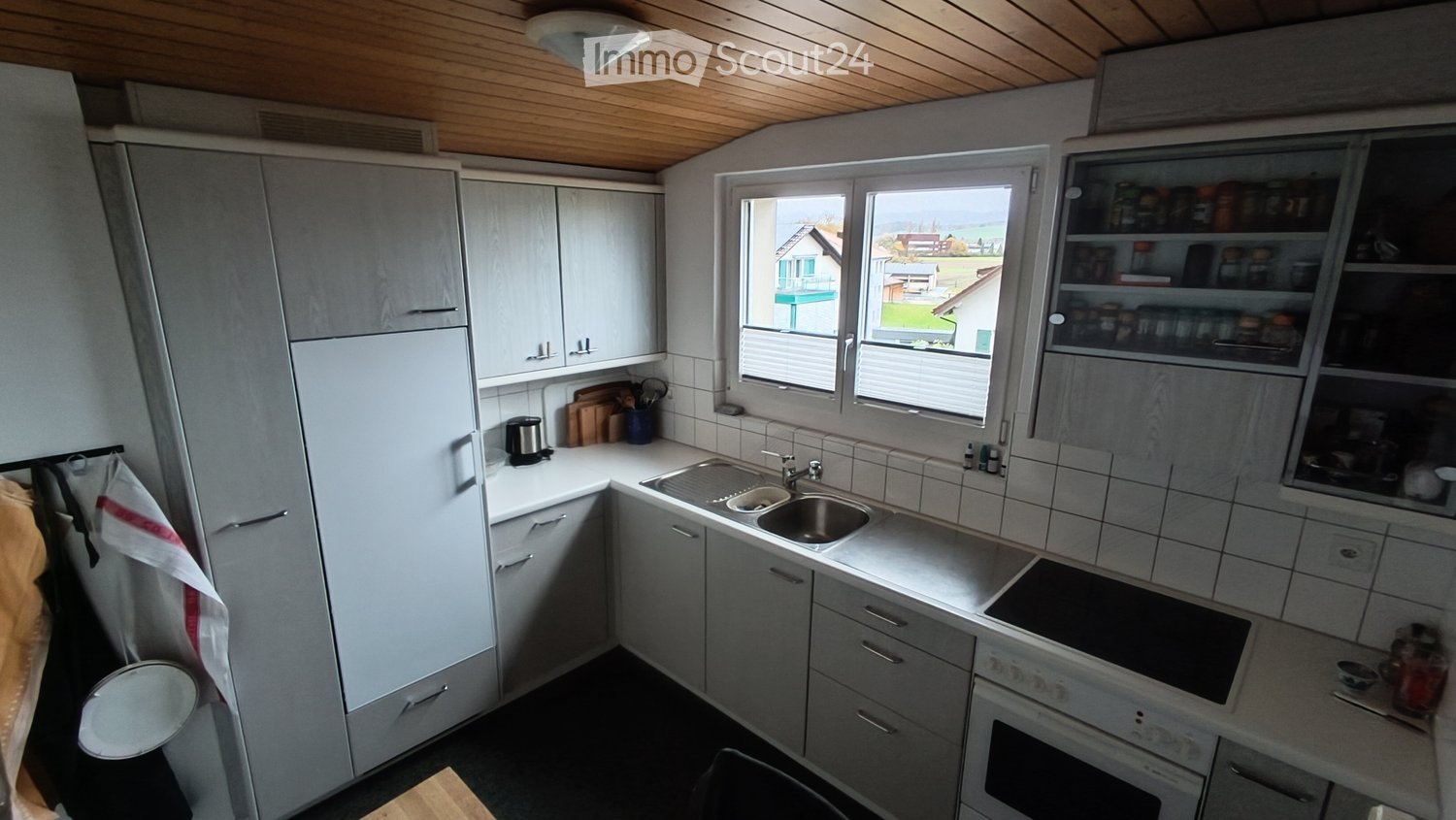 Kitchen: white cabinets, black countertop, double sink, gas stove, refrigerator, white and wooden ceiling