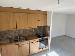 empty kitchen with wooden cabinets, tiled floor, sink, faucet, and oven