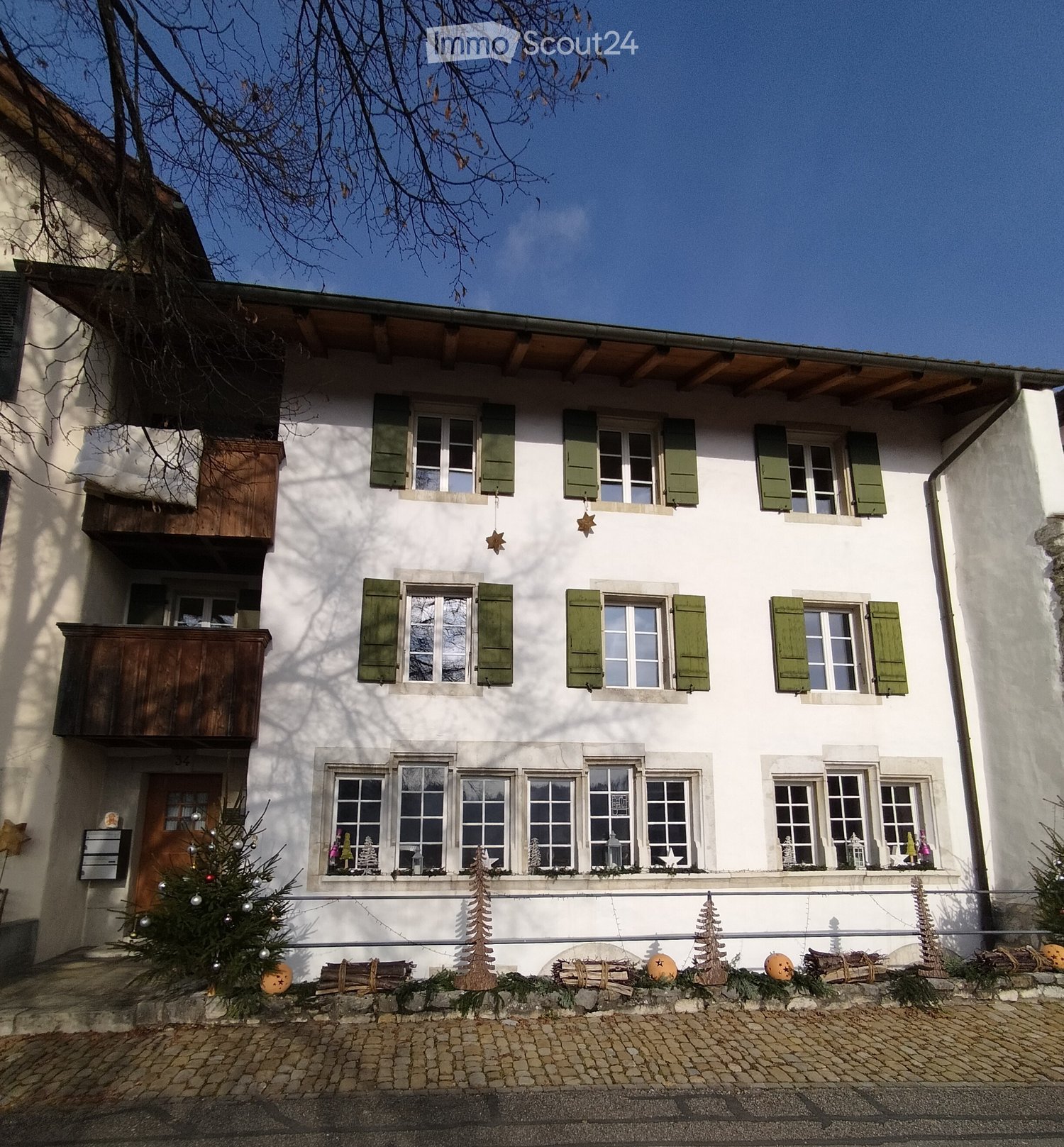 3 story house, white painted, green shutters, front door, small porch, multiple windows, stone path, holiday decoration