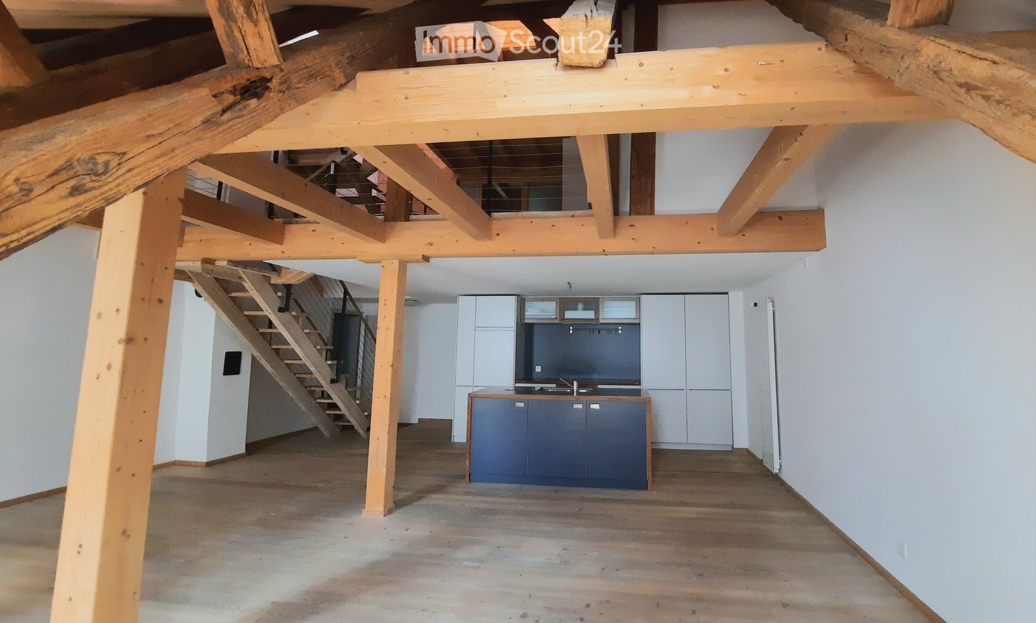 loft style room with wooden beams, wooden floor, kitchen with sink and stove, staircase
