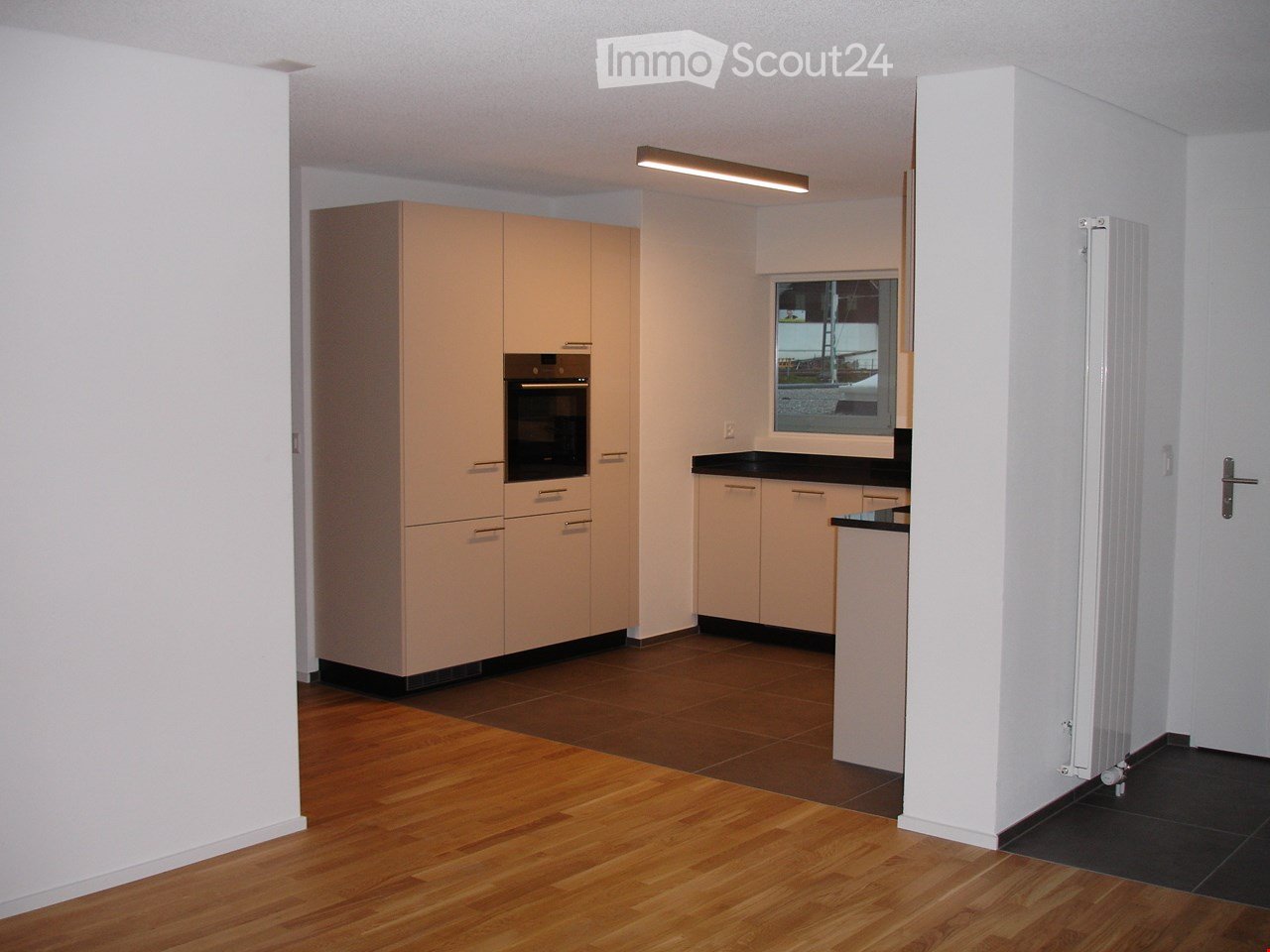 Kitchen with cabinets, black counter top, windows, and wooden floor