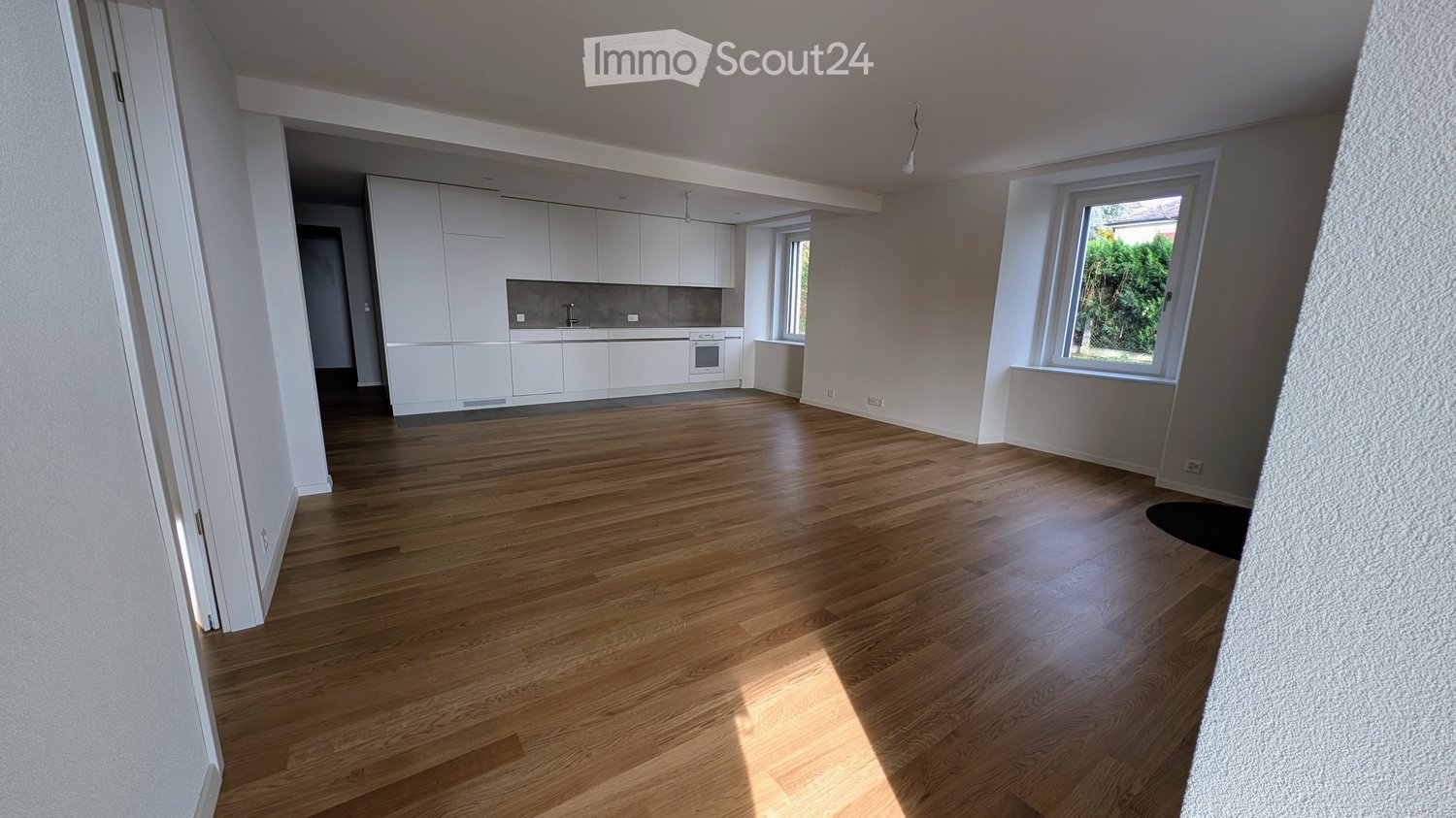 wooden floor, white walls, kitchen with oven and sink, windows