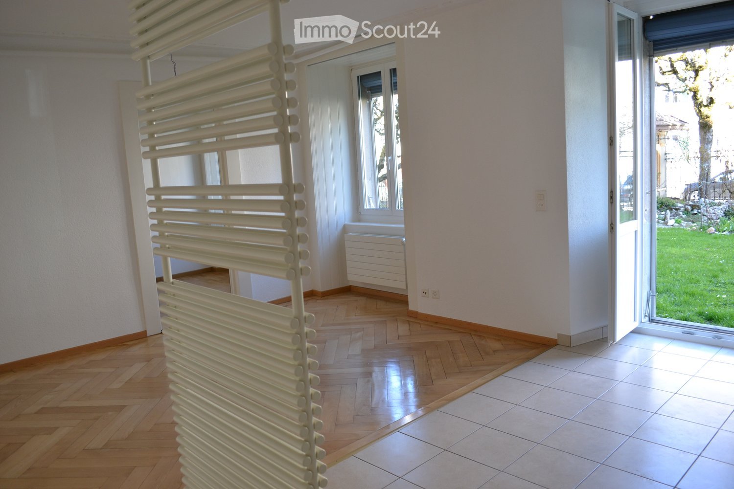 Open space with parquet floor, windows with views, glass door, white walls, power outlets