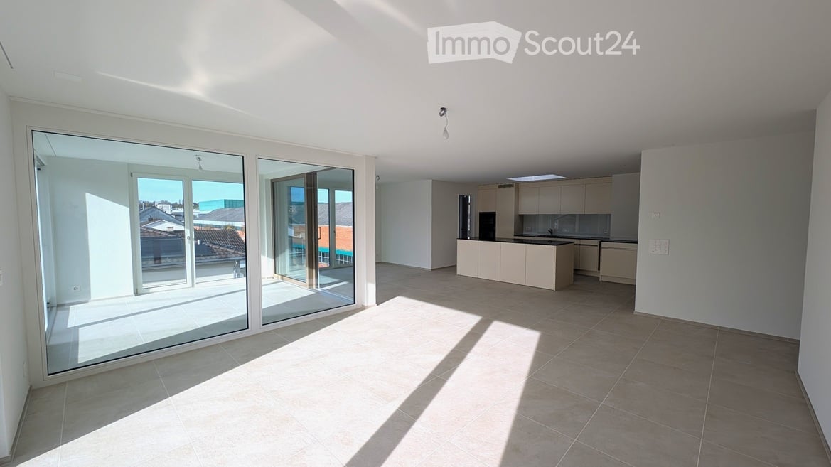 open plan living area with large sliding glass doors leading to balcony, tiled floor, kitchen island