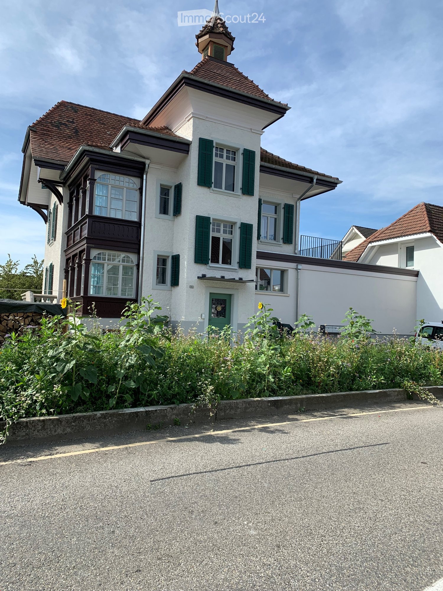 2 story white house, green shutters, brown roof, balcony