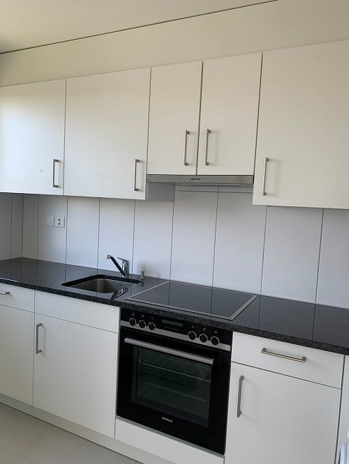 modern kitchen, stainless steel dishwasher, granite countertop, white cabinets, black countertop, oven, sink, faucet