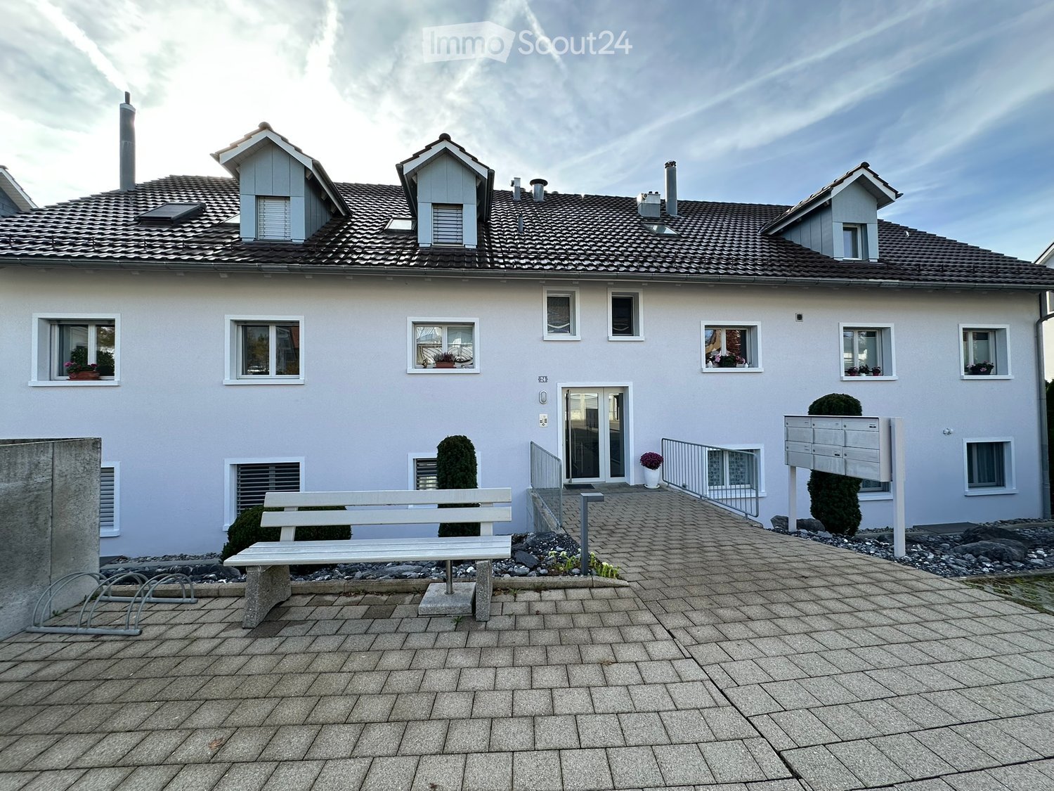 2 story apartment building, white exterior, gray roof, multiple windows, paved entrance
