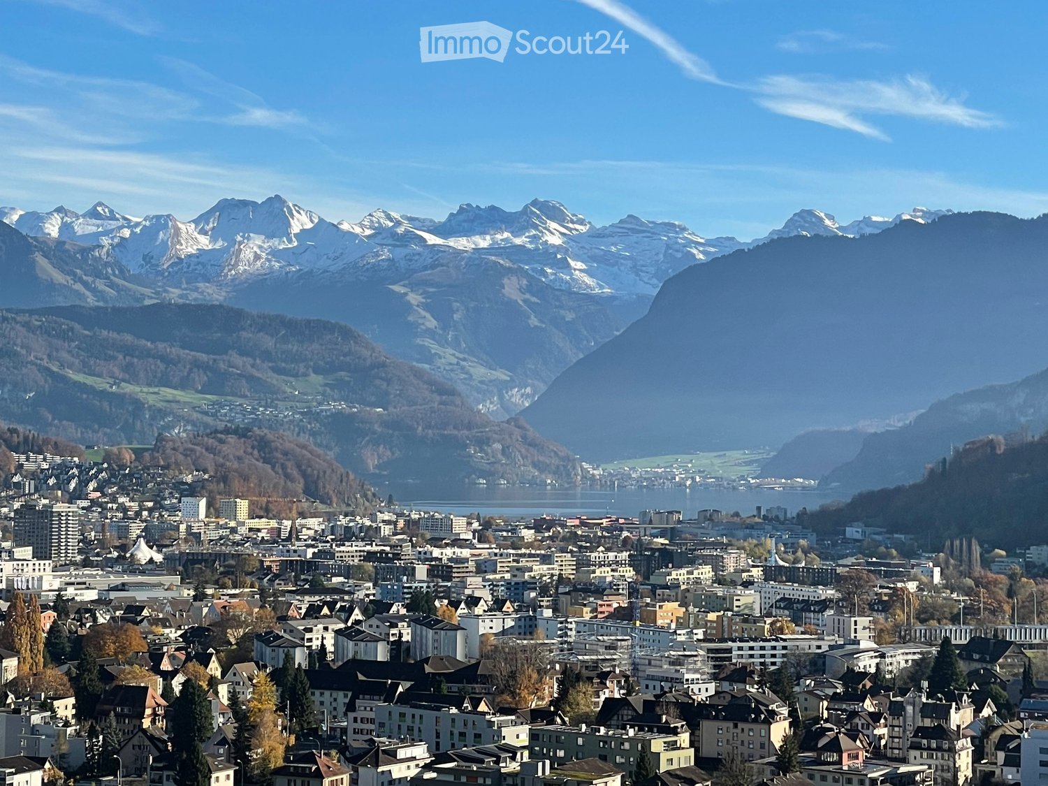 mountainous terrain, snow-capped peaks, city with many buildings, bodies of water