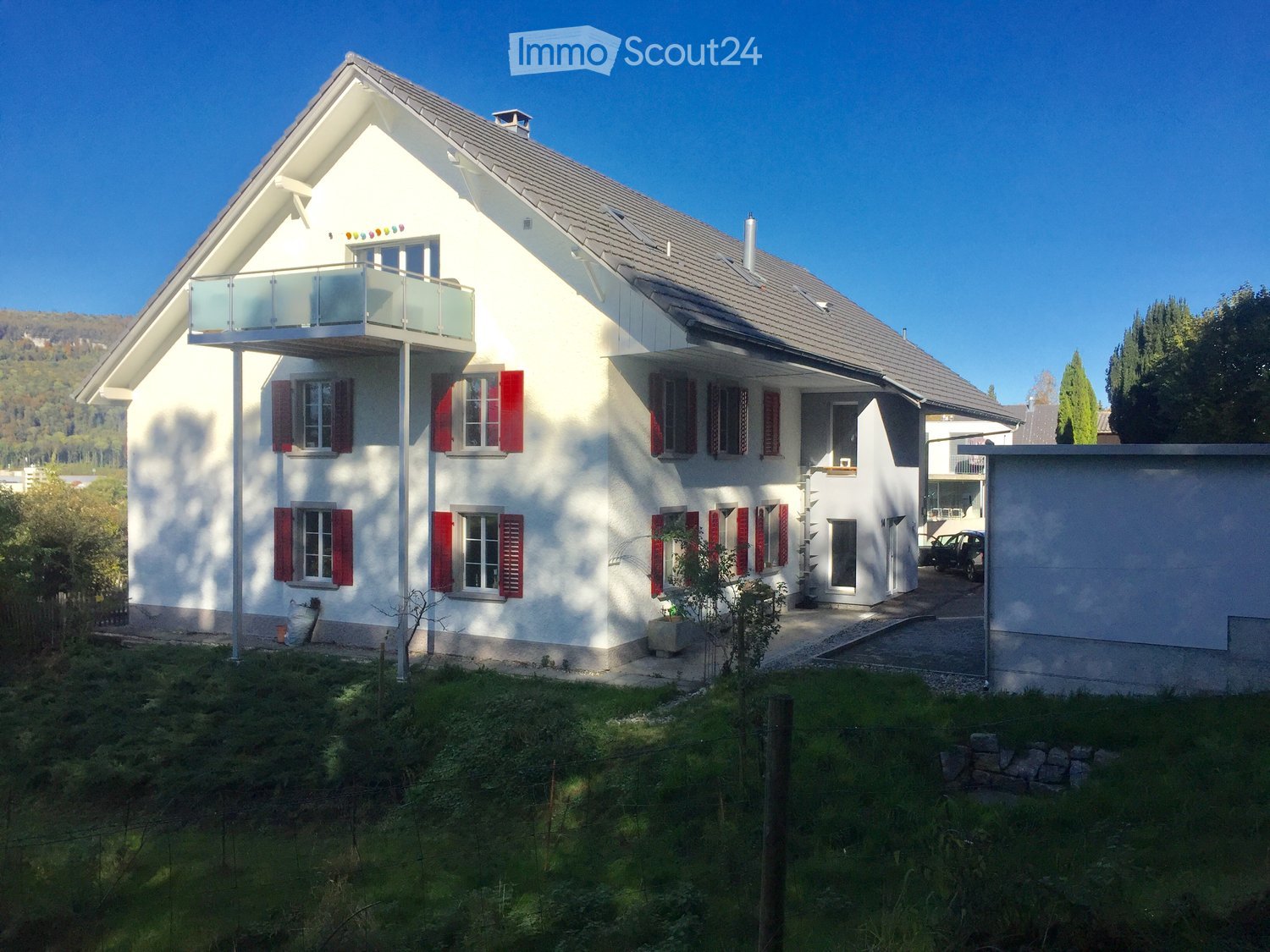 two story house, white exterior, red shutters, gray roof, garage, balcony, well maintained grass yard, distant mountains