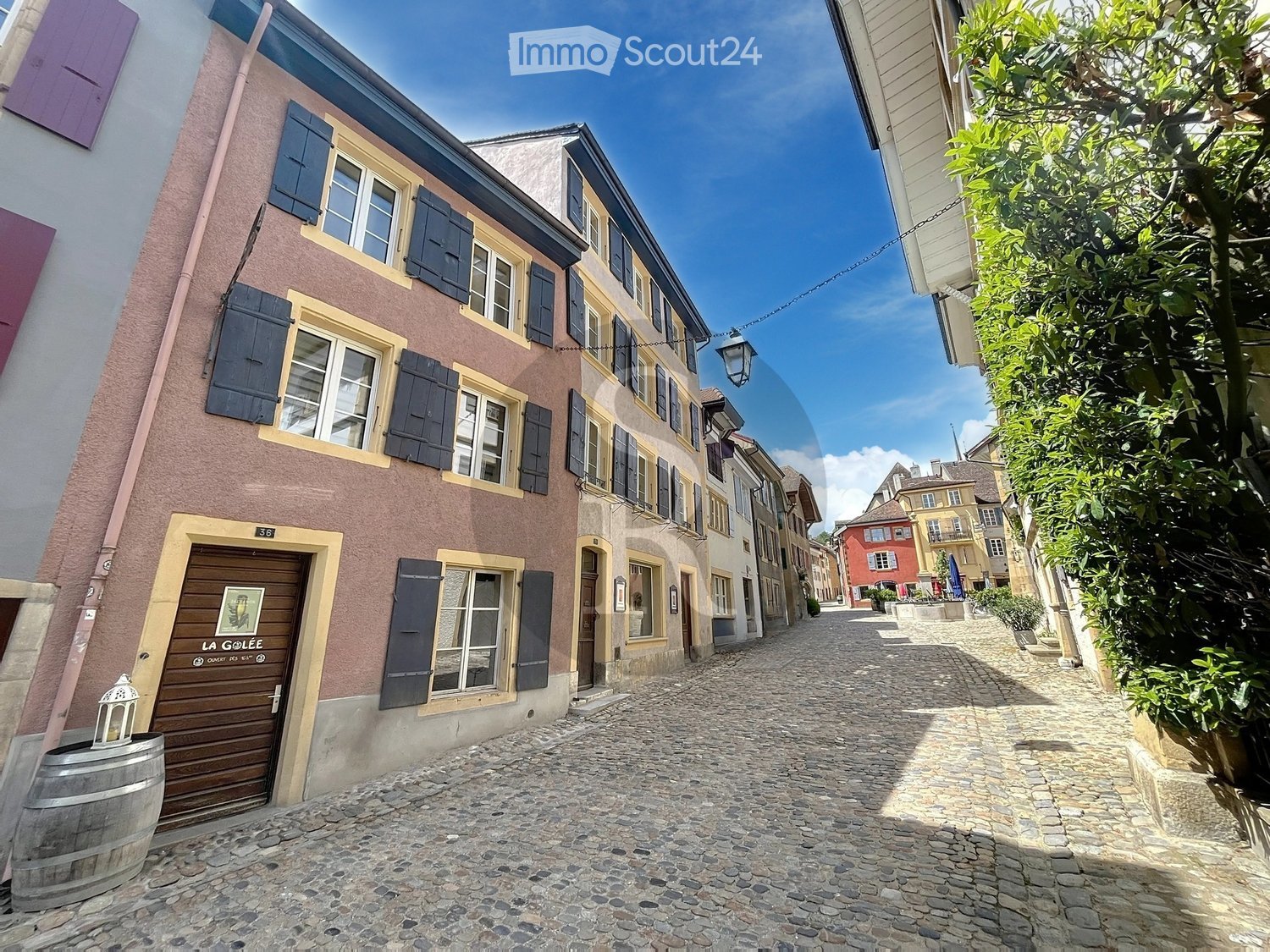 Cobblestone street, multistory buildings, arched entrance, lamp, barrel