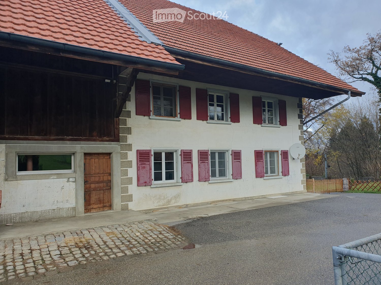 2-story house, white painted, red roof, red shutters, brown wooden door, brick paving, fenced garden