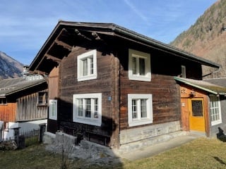 small wooden house, wooden siding, white trim windows, orange door, stone steps, sloped roof, front yard with grass
