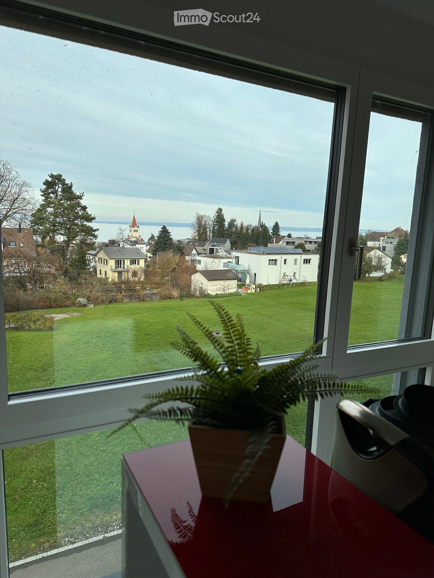 a view from a large window, overlooking a landscape with green fields and trees
