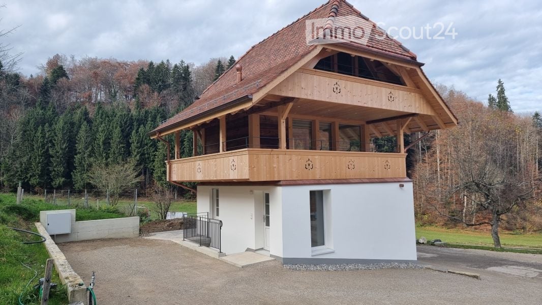 Wooden and white house, with balcony, in a forest background