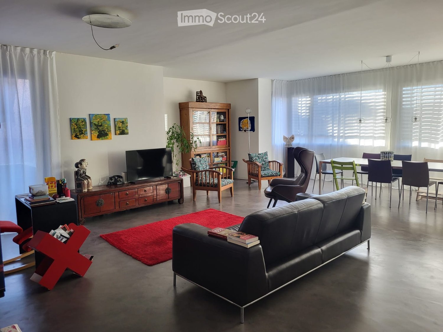 living room, black leather couch, wooden cabinet with television, wooden dining table, wooden chairs, rug