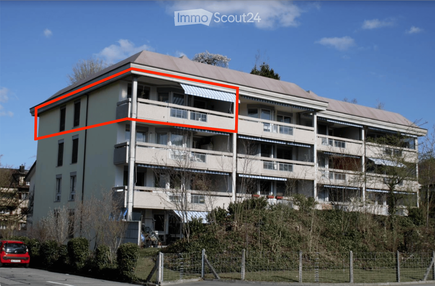 5 story building with beige walls, red roof, many balconies and windows