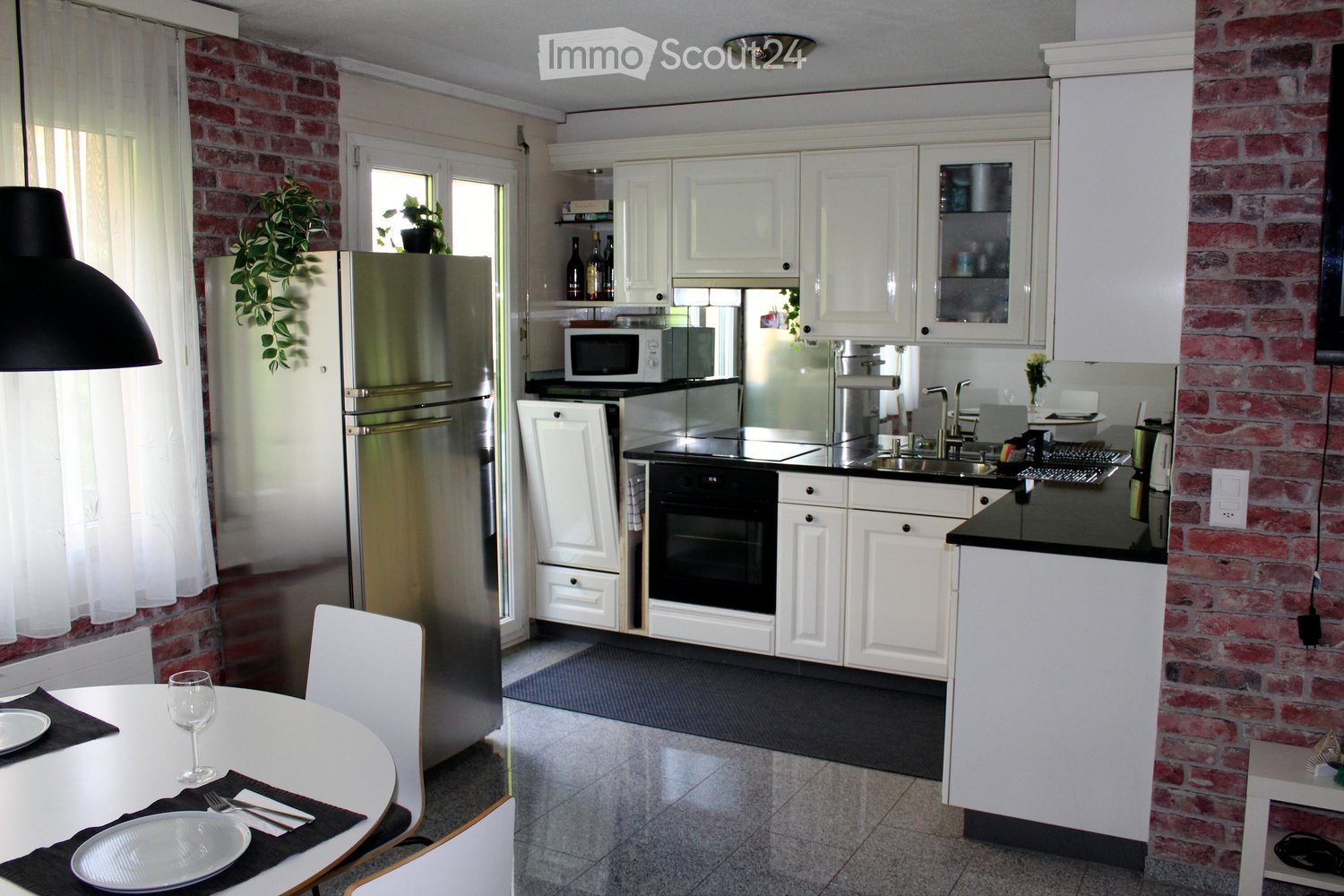 white kitchen, stainless steel refrigerator, black countertop, white dining table, wine glasses