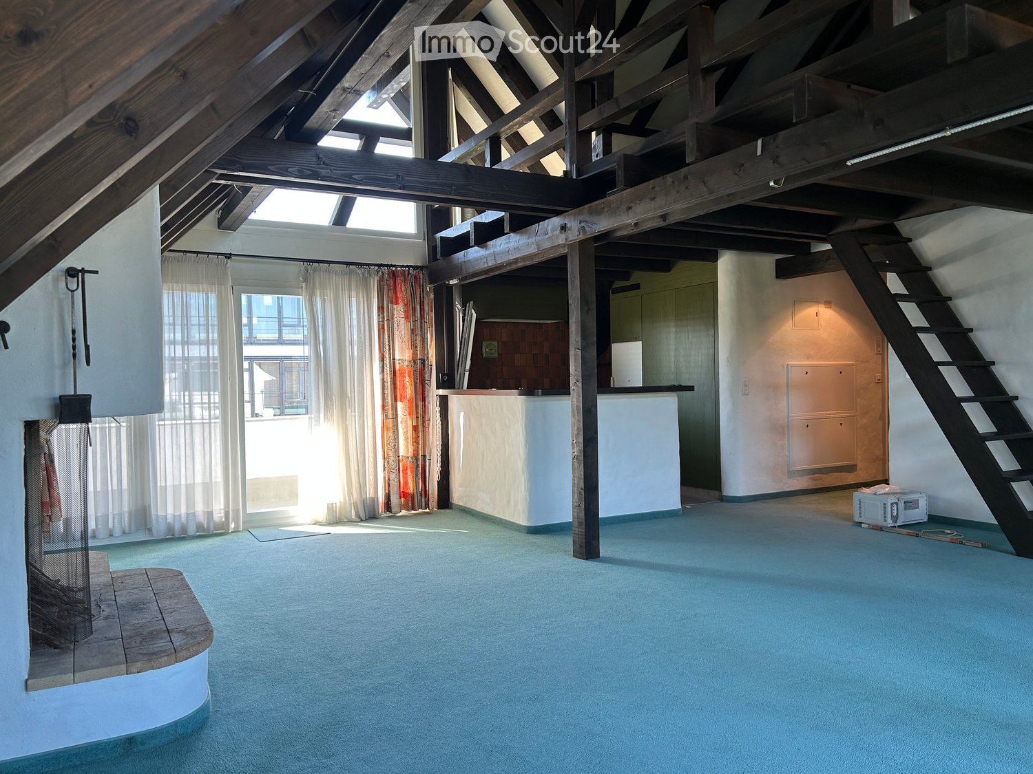room in an attic, fireplace, carpeted floor, wooden beams, wooden stairs