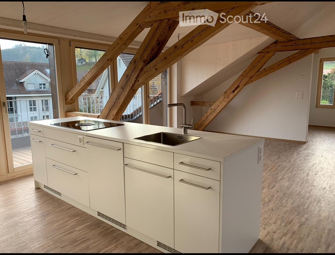 modern kitchen, central island with stovetop and sink, lots of cupboards, wooden beams, open balcony