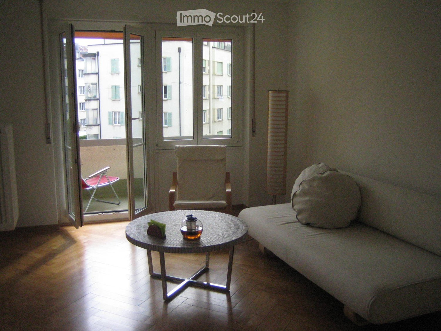 white sofa, coffee table, chair, glass door, small balcony, radiator, parquet floor