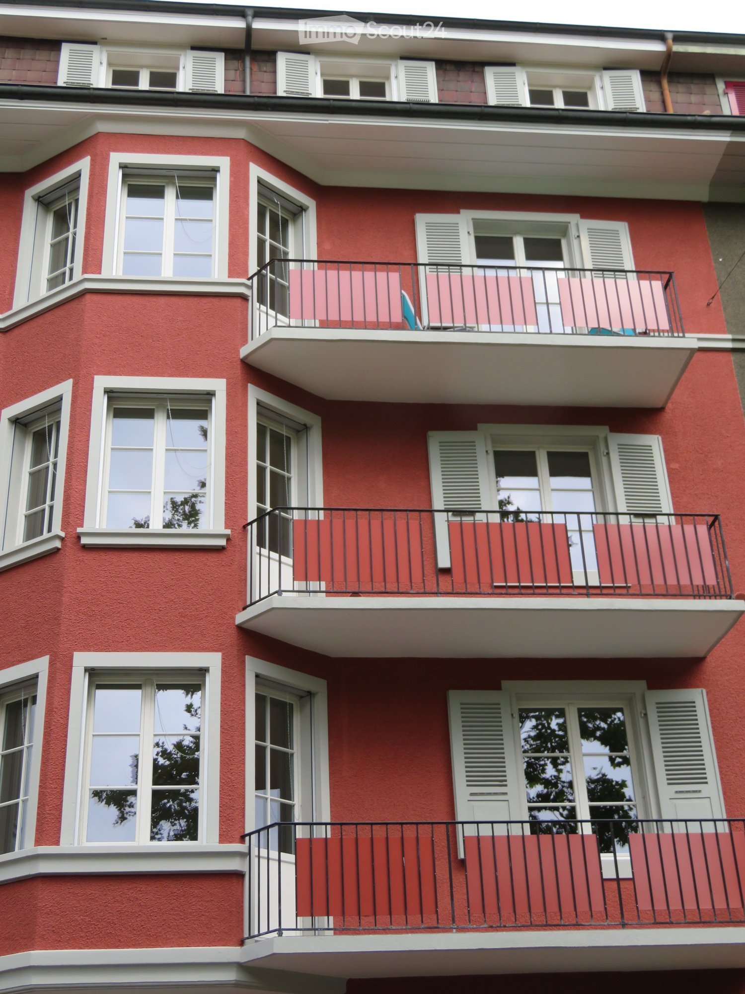 3 story building, red walls, white windows, multiple balconies