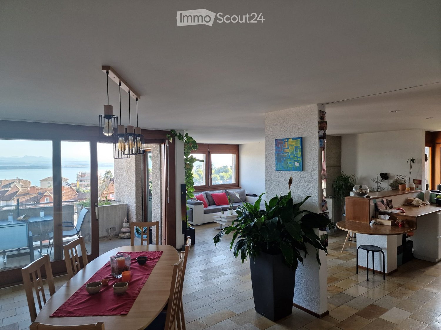 dining area with dining table and chairs, balcony with outdoor seating, potted plants, kitchen island, couches, side table, artwork, open door to bedroom, chandelier